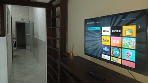 Un salón con un televisor de pantalla plana mostrando la interfaz de una plataforma de streaming.