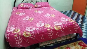 A bed with a floral bedspread, a metal frame, and a checkered floor. - Guest house transit to Langawi Island (Kuala perlis)