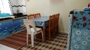 A dining area with a table and chairs, a patterned rug, and a kitchen counter. - Guest house transit to Langawi Island (Kuala perlis)