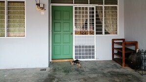 A green door with a metal gate, a window with a grid pattern, and a number '21' sign on the wall. - Guest house transit to Langawi Island (Kuala perlis)