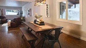A dining area with a wooden table, benches, and a 'BAKERY' sign on the wall.