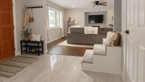 A modern living room with a sofa, a television, and a ceiling fan.