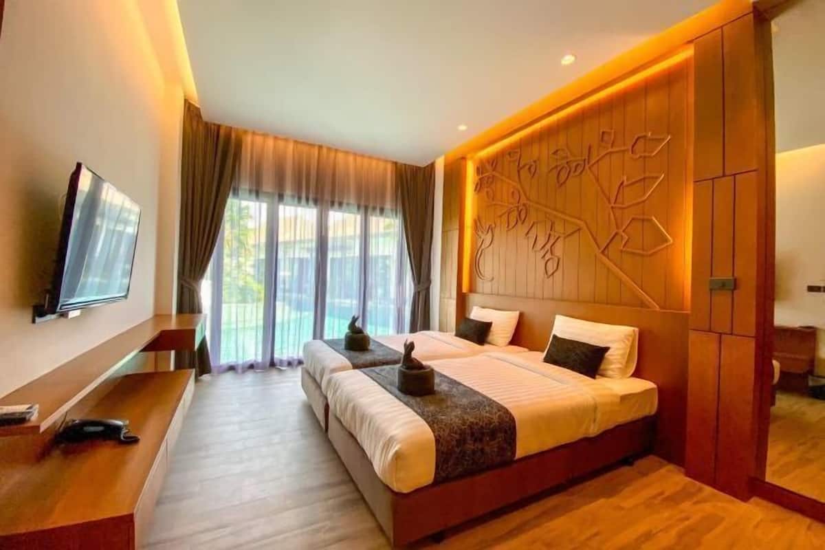 A hotel room with a large bed, a desk, a television, and a window with curtains.
