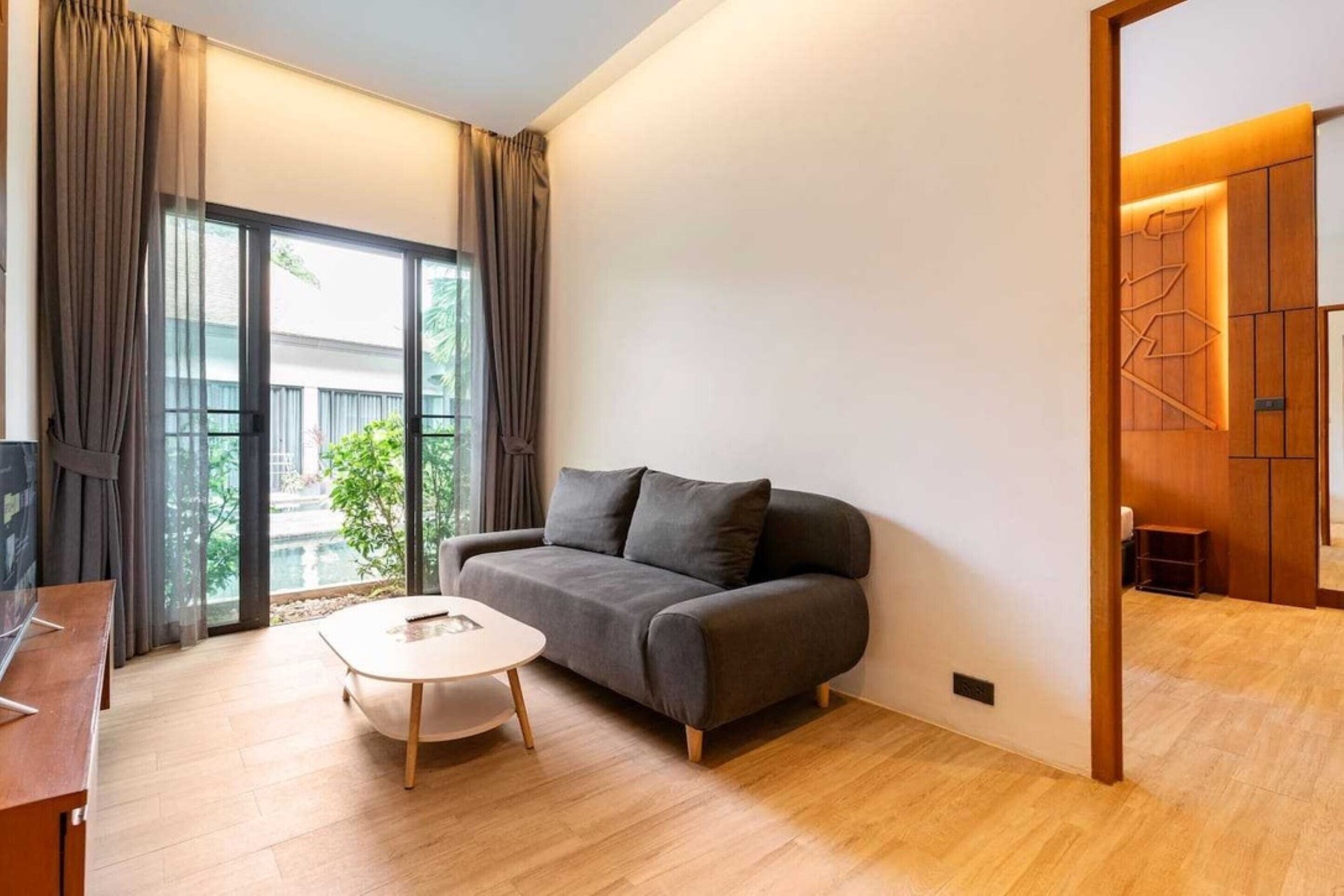 A modern living room with a grey sofa, a round coffee table, and a TV on a wooden table.