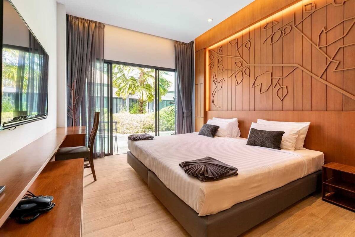 A modern hotel room with a large bed, a desk, and a TV.