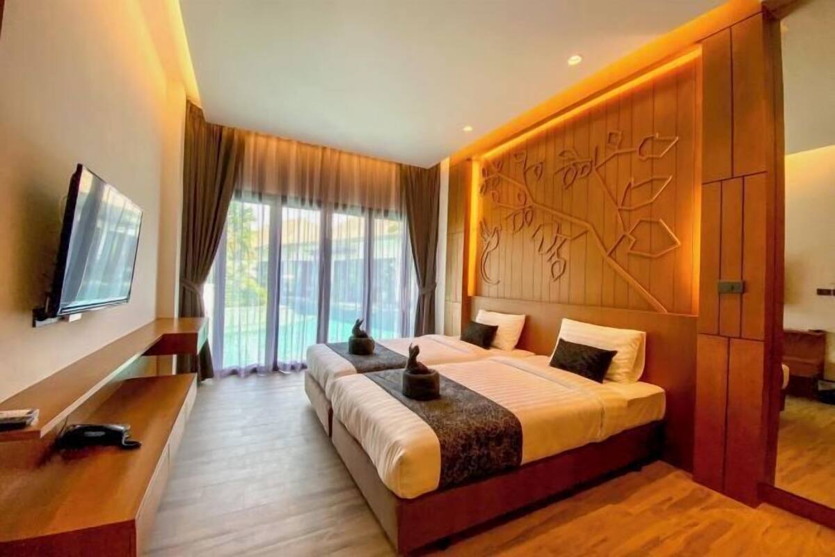 A hotel room with a large bed, a flat-screen TV, a wooden headboard, and a view of the outdoors.