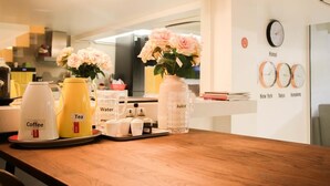 A hotel room with a wooden table set with coffee, tea, water, and juice containers, and a vase with flowers. - Banana Inn Hostel (Hanoi)
