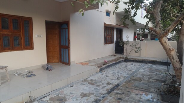 A courtyard with a tiled floor, a wooden door, and a small tree. - Room in a Villa 3km from City Center, 1km from IT park (Udaipur)