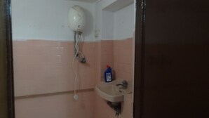 A bathroom with a white ceiling, pink walls, a white sink, and a bottle of blue liquid. - Room in a Villa 3km from City Center, 1km from IT park (Udaipur)