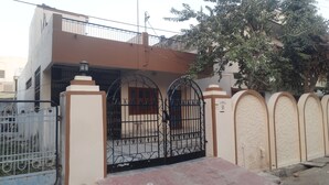 A residential building with a gated entrance, a balcony, and a tree in front. - Room in a Villa 3km from City Center, 1km from IT park (Udaipur)