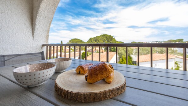 Un balcón con una mesa de madera, dos cuencos y dos pasteles sobre una tabla de madera.