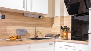 Una cocina moderna con armarios blancos, un protector contra salpicaduras de madera, un lavamanos de acero inoxidable y un portalapices colorido.