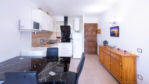 Una cocina compacta con una mesa de comedor, sillas, microondas, refrigerador y un mueble de madera.