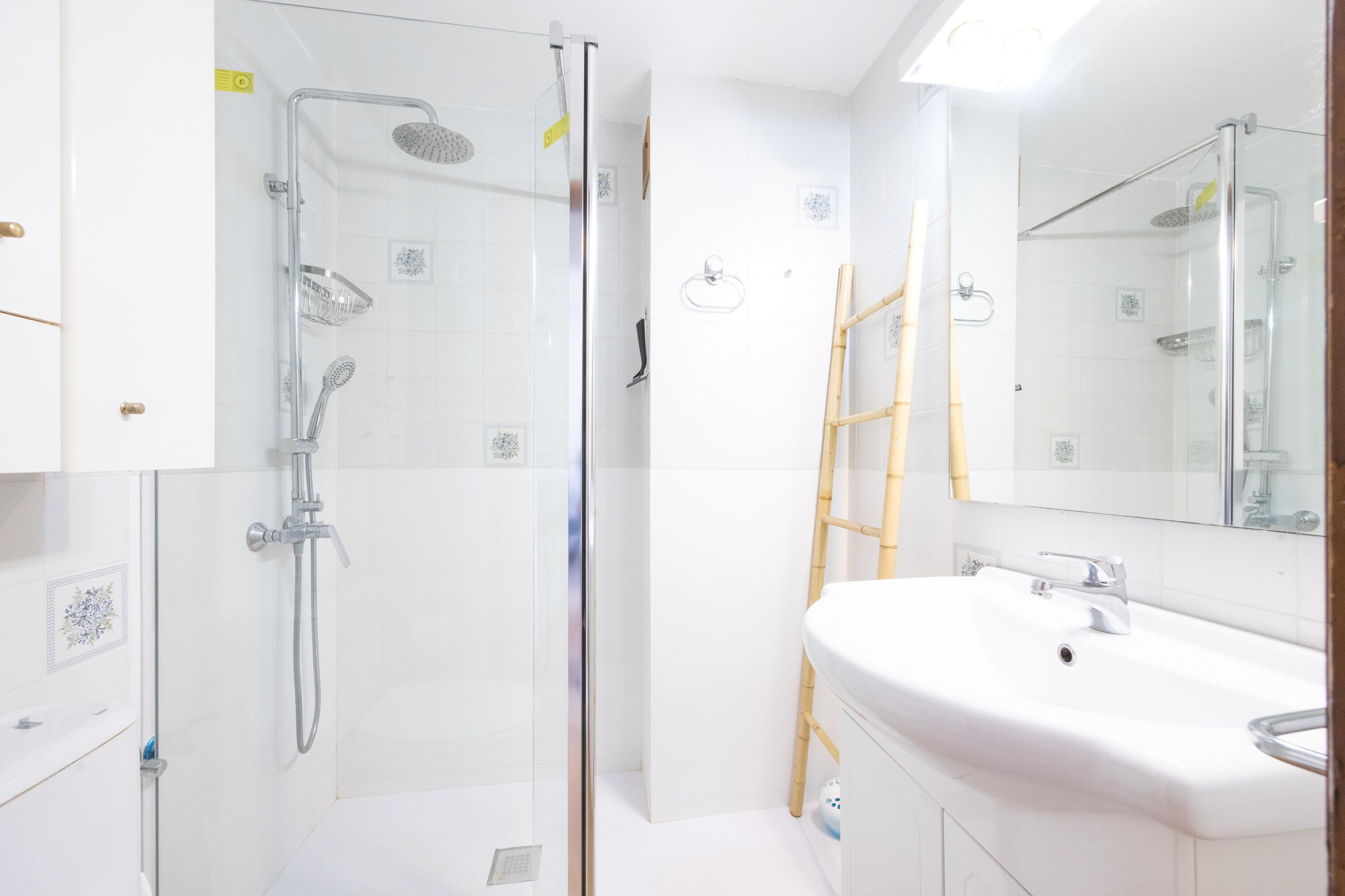 A modern bathroom with a glass-enclosed shower, a white sink, and a mirror.