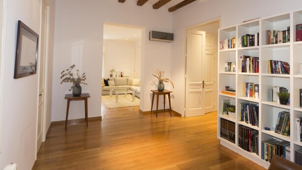 Un vaste espace de vie doté d’un plancher en bois, d’une bibliothèque remplie de livres et d’un coin salon confortable avec un canapé et une table basse.