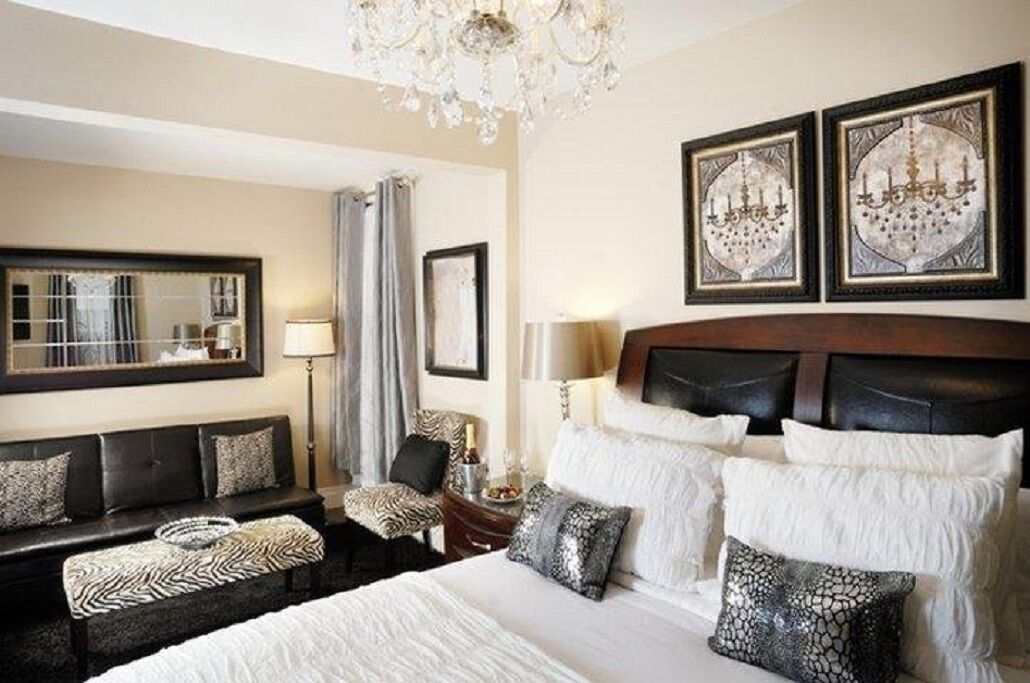 A hotel room with a large bed, a sofa, a chair, and a chandelier.