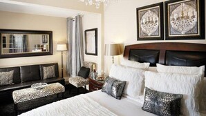 A hotel room with a large bed, a sofa, a chair, and a chandelier. - Historic Boutique Hotel (Branson)