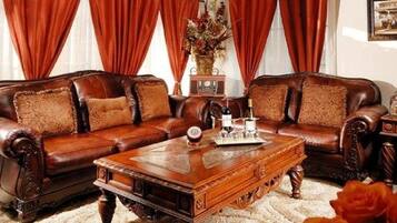 A traditional living room with a brown leather sofa set, a wooden coffee table, and red curtains.