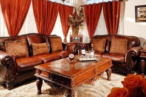 A traditional living room with a brown leather sofa set, a wooden coffee table, and red curtains. - Historic Boutique Hotel (Branson)