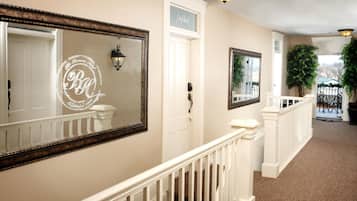 A hallway with a white door labeled "Notebook," a large mirror with a decorative frame, and a potted plant.