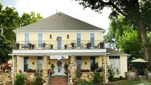 A two-story building with a balcony, stone columns, and a front entrance with a sign that reads "Hotel." - Historic Boutique Hotel (Branson)