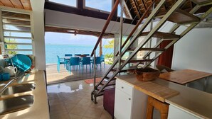 Una cucina con vista sul mare, un'area pranzo con sedie blu e una scala.