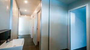 A modern hotel corridor with a large bathroom featuring a white sink and a mirror. - So Good Haad Rin Hostel (Ko Pha-ngan)