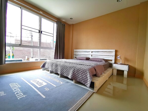 A bedroom with a bed, a nightstand, a lamp, and a window with curtains.