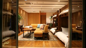 Een moderne hotelkamer met een houten vloer, een bank, een bed, een kleine tafel en een stoel.