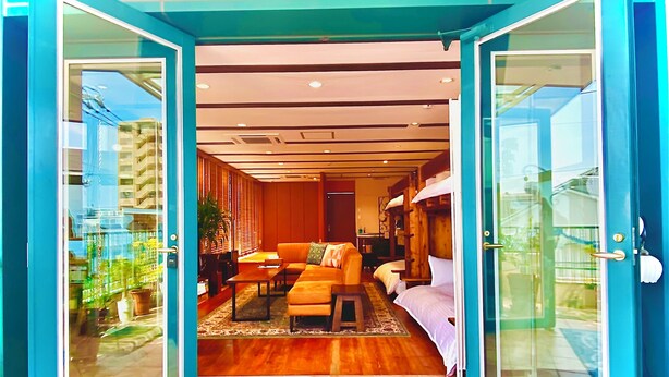 Een hotelkamer met houten vloer, een bank, een tafel en een bed.