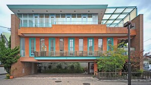 Een modern gebouw met twee verdiepingen, een plat dak, grote ramen en een balkon.