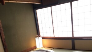 A room with tatami mats, a futon bed, a shoji screen, and a traditional Japanese-style lamp. - Ichii no Niwa (Takayama)