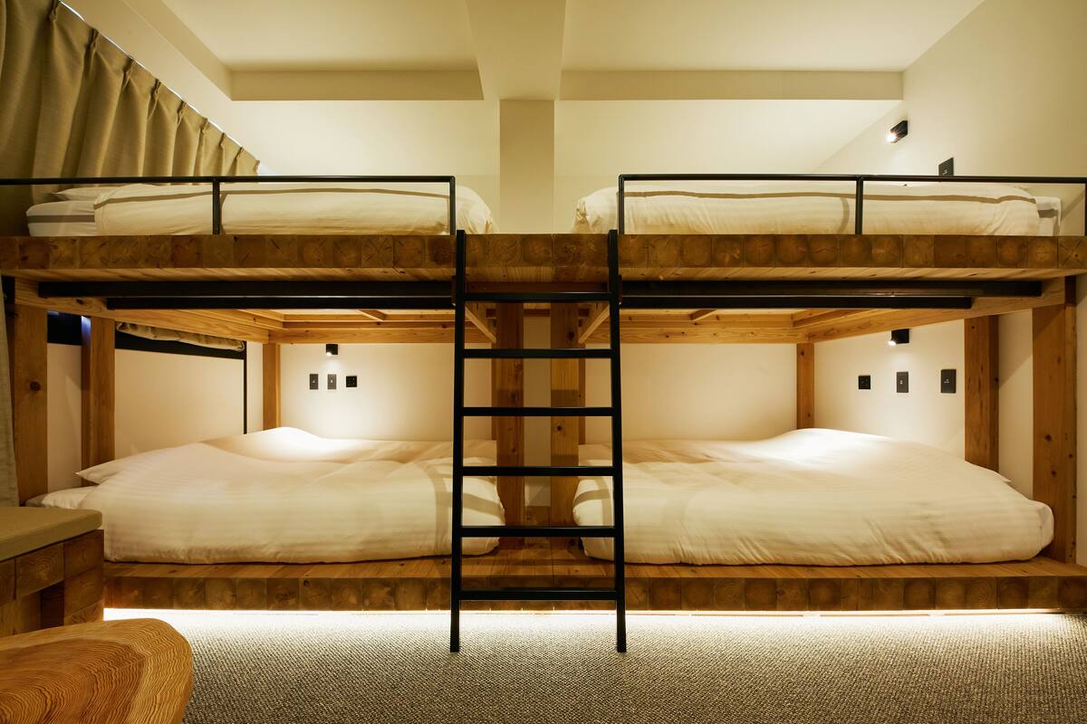 Une chambre avec un lit superposé, une échelle, des poutres en bois et un petit bureau.