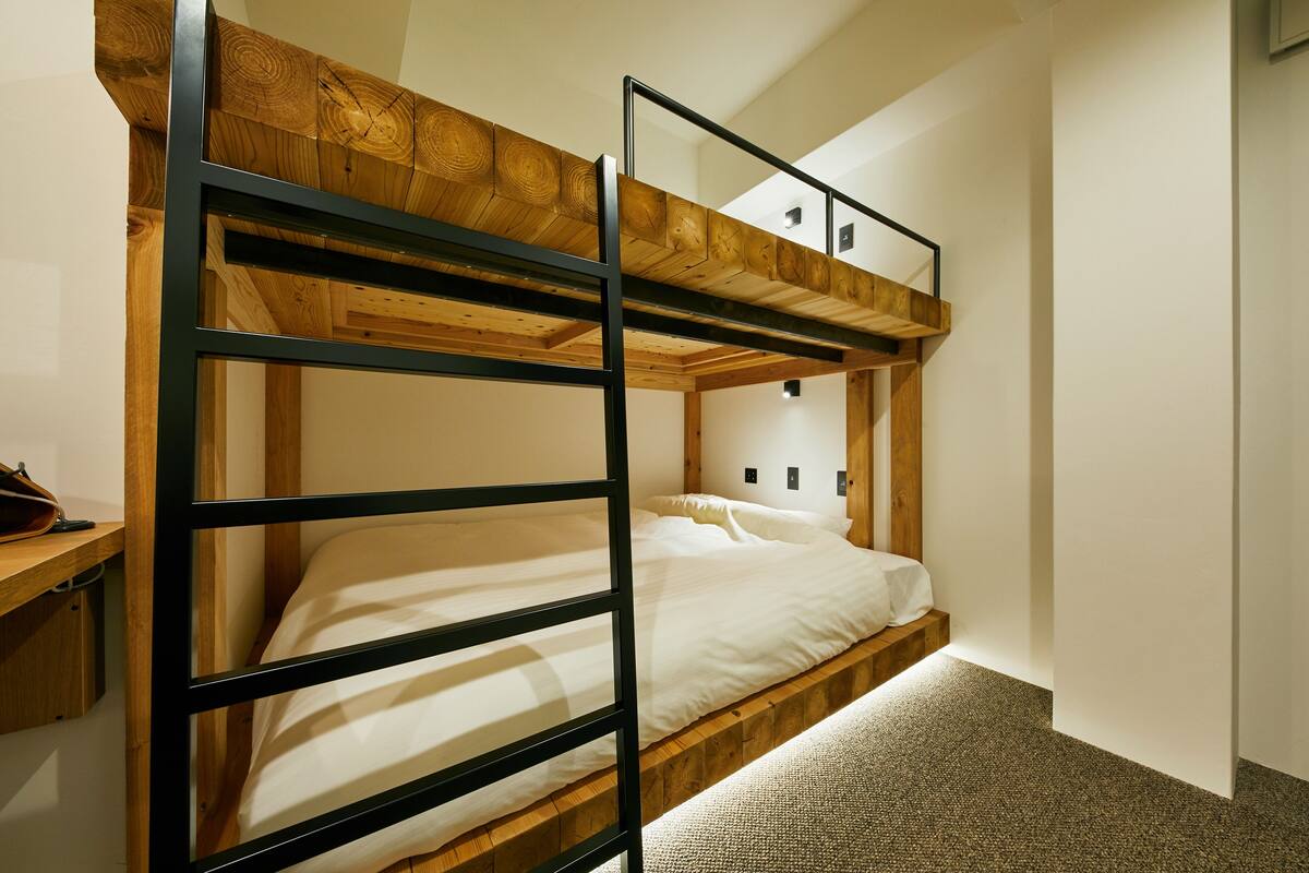 Un lit superposé avec une tête de lit en bois et un lit inférieur équipé d’un matelas et d’oreillers.