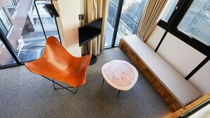 A modern room with a leather chair, a round wooden table, a bench, and a large window offering a city view. - mizuka Daimyo 7 - unmanned hotel - (Fukuoka)