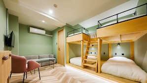 Une pièce comprenant un lit superposé, un canapé, une chaise et un bureau en bois.