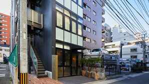 A modern building with a black facade, large windows, and a visible entrance with a staircase. - mizuka Daimyo 7 - unmanned hotel - (Fukuoka)