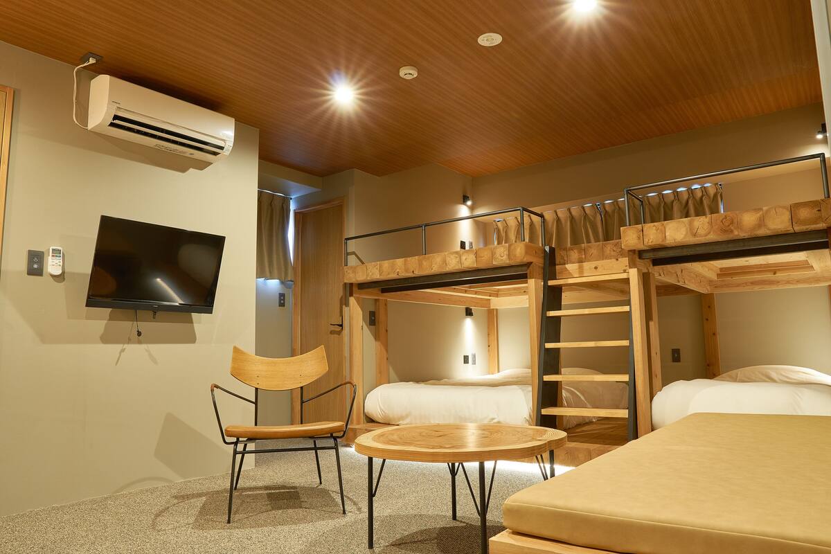 Une chambre avec un lit superposé, une télévision, une chaise, une table et un climatiseur.
