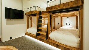 A room with bunk beds, a television mounted on the wall, and a carpeted floor. - mizuka Daimyo 7 - unmanned hotel - (Fukuoka)
