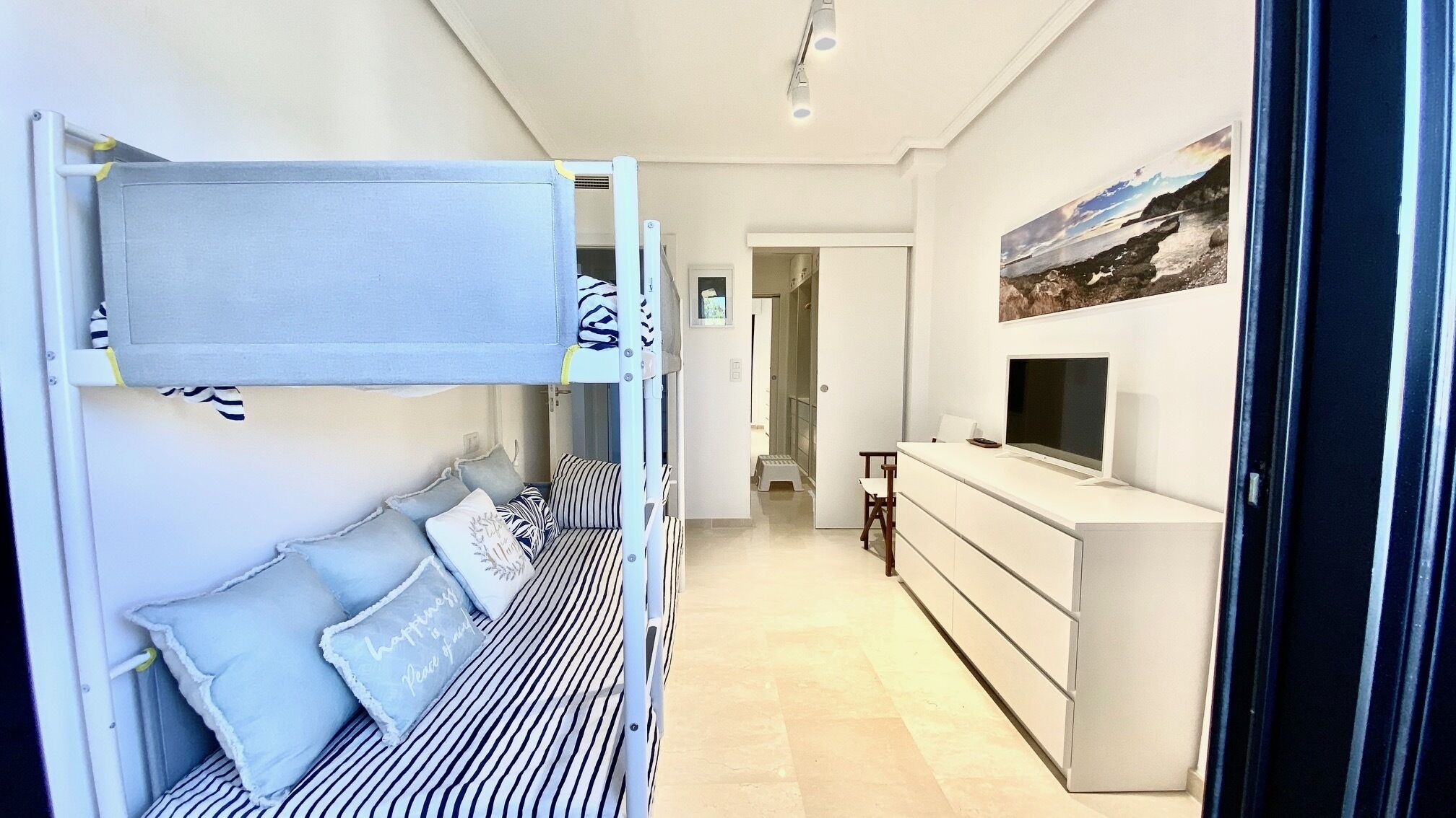Un dormitorio con literas, un televisor y un cuadro en la pared.