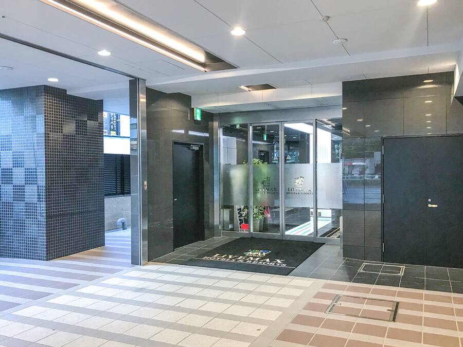 A modern hotel lobby with a checkered floor, a reception desk, and a glass elevator.