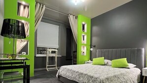 Ein modernes Schlafzimmer mit einem großen Bett, einem Schreibtisch mit Lampe und Blick ins Freie.