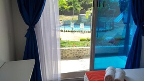 Une chambre avec un lit, une table et une vue sur une piscine et un espace extérieur.