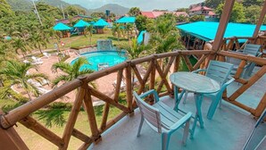 Une terrasse en bois avec une piscine, des chaises et des parasols.