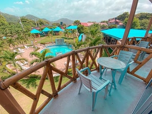 A wooden deck with a pool, chairs, and umbrellas.