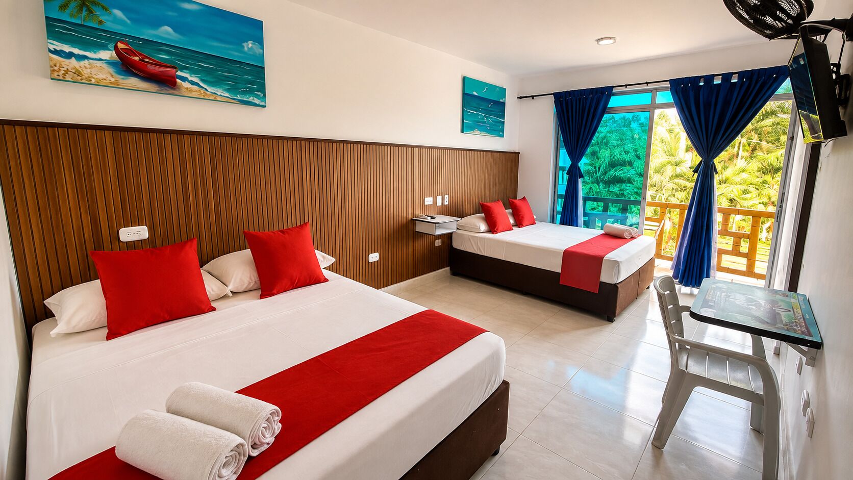 Ein Hotelzimmer mit zwei Betten, einem Holzkopfteil, einem kleinen Tisch und Blick auf Grünfläche.