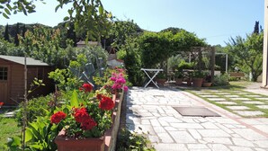 A garden with a stone pathway, potted plants, and a wooden structure. - CASA CIRILLA - Casa Cirilla (Marciana)