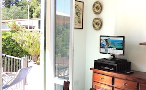 A room with a large window, a flat-screen TV on a wooden dresser, and two decorative plates on the wall.