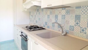 A kitchen with a gas stove, sink, and patterned backsplash. - CASA CIRILLA - Casa Cirilla (Marciana)