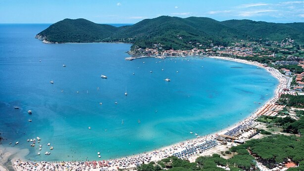 An aerial view of a coastal town with a beach, boats, and surrounding hills. - CASA CIRILLA - Casa Cirilla (Marciana)